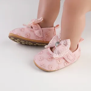 Macro view of pink baby girl princess shoes with delicate lace bow and floral embroidery