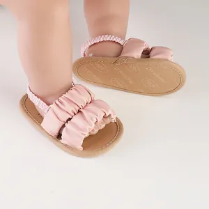 Detailed view of pink baby prewalker sandals with ruffled straps and non-slip soles