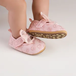 Close-up of pink baby princess shoes with floral embroidery and lace bow details.
