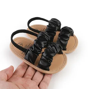 Detailed view of black cloud ruffled baby sandals featuring soft tan soles and elastic straps