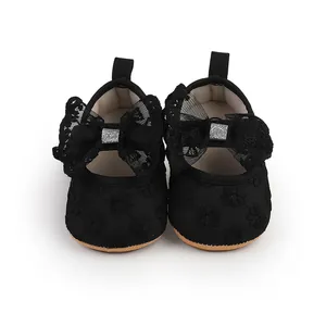 Detailed view of black infant girl walking shoes with delicate lace bow and soft sole.
