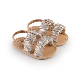 Close-up of baby girl shimmery gold walking sandals with ruffled straps