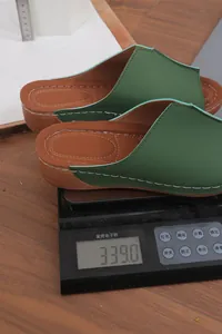 Detailed view showing the light weight of the green wedge sandals on a scale for comfort.