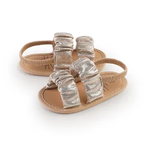 Close-up of sparkling gold ruffled baby sandals with soft soles and elastic straps