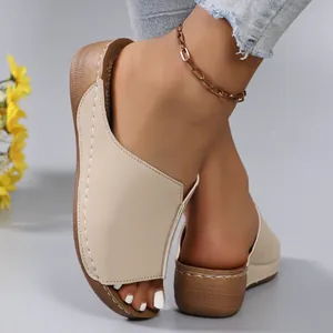 Detail view of women's beige wedge sandals with peep toe and white contrast stitching.