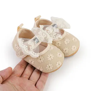 Close-up of beige lace baby princess shoes with delicate flower embroidery and bow detail.