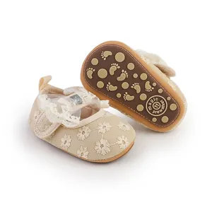 Close-up of beige lace baby shoes showing delicate floral patterns and soft soles
