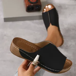 Close-up detail of black peep-toe wedge sandals featuring elegant white contrast stitching