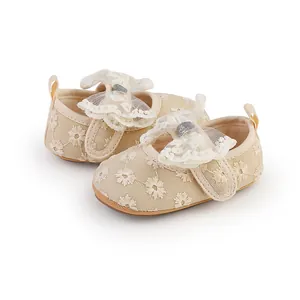 Detailed close-up of cream baby girl lace shoes with floral embroidery and a bow