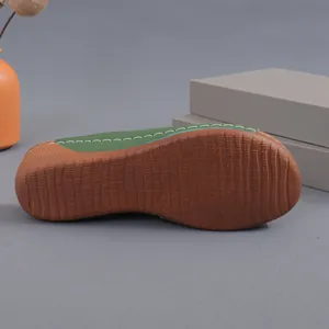 Detailed bottom view of green wedge sandal showing anti-slip brown textured sole
