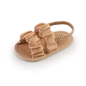 Close-up detail of soft pleated straps on tan baby girl summer walking sandals for infants.