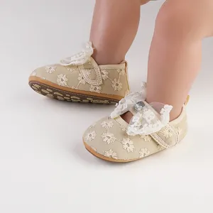 Close-up of beige floral lace baby shoes with bow and soft rubber sole