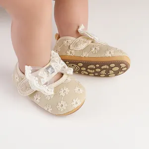 Close-up of beige lace infant princess shoes with floral embroidery and bow detail