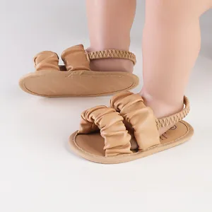 Close-up of tan ruffled baby walking sandals with elastic back strap and soft sole