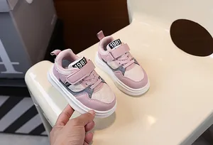 Detailed close-up of pink children's sneakers with velcro straps and thick white soles