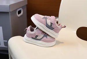 Stylish pink and beige children's fashion sneakers with thick soles displayed on a chair