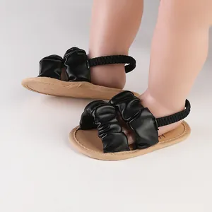 Detailed view of baby sandals featuring black ruched cloud straps and soft tan soles