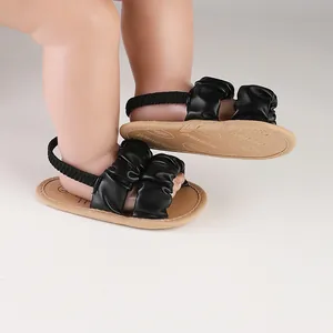 Close-up of black ruffled cloud baby sandals with soft tan soles and elastic straps
