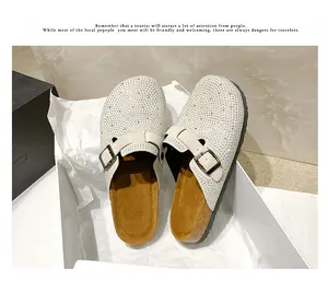 High-quality detail shot of sparkling rhinestone-embellished clogs in white inside a box