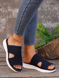 Vue détaillée des sandales compensées en maille bleue portées par un mannequin dehors.