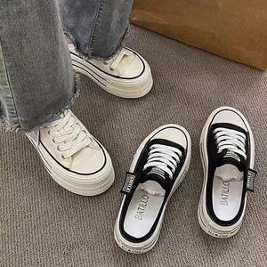 Close-up detail of stylish women's thick-soled canvas mule sneakers in black and white.