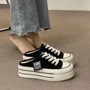 Close-up of black platform mule sneakers with thick white soles and canvas upper.