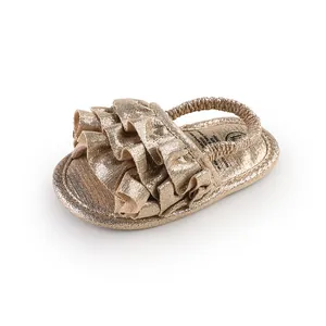 Detailed macro view of sparkling gold ruffled baby pre-walker shoes with elastic heel strap.