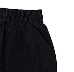 Detalle de la cintura elástica y el bolsillo en pantalones cargo negros de pierna ancha para hombre