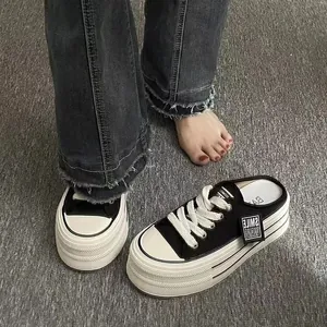 Close-up of stylish black thick-sole platform backless sneakers on a grey carpet