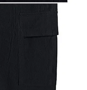 Primer plano detallado del gran bolsillo lateral con solapa de estos pantalones cargo negros.