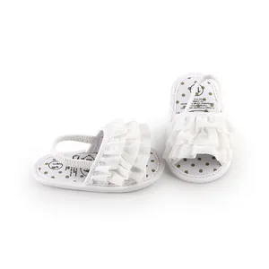 Close-up of white ruffled baby sandals with polka dot insole for newborn girls