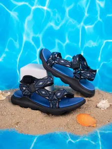 Sandali blu e neri per bambini con motivo geometrico sulla sabbia della spiaggia