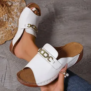 Vista dettagliata di sandali con zeppa bianchi open-toe con elegante catena dorata