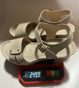 Gewichtsanzeige einer beigen Keilsandalette mit Hohlnieten auf einer Digitalwaage