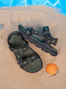 Dettaglio dei sandali da spiaggia per ragazzi con motivi geometrici su fondo sabbioso