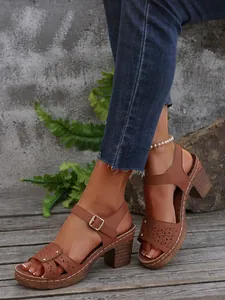 Nahaufnahme der braunen High-Heel-Sandalen mit Durchbruchmuster und Nieten (81 chars)