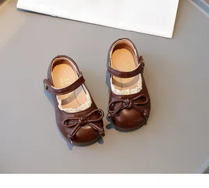 Détail de chaussures de princesse en cuir marron pour filles avec nœud décoratif et dentelle