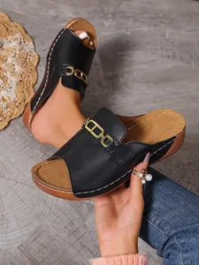 Eleganti ciabatte con zeppa nera con una catena dorata alla moda e punta aperta.