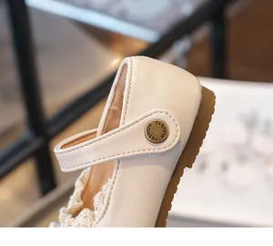 Gros plan d'une chaussure en cuir pour fille crème avec bordure en dentelle et boucle