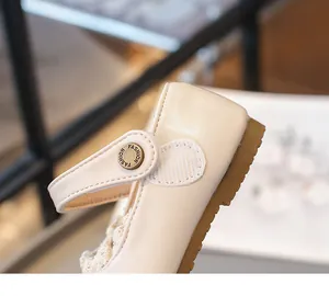 Gros plan sur une chaussure beige pour fille avec bride velcro et détails en dentelle.