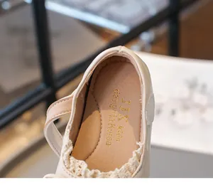 Détail de chaussure plate en cuir beige pour enfant avec dentelle et logo doré chic