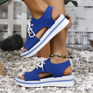 Detailed view of blue platform sandals with white laces on a pebble beach background