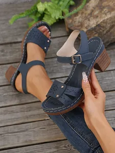 Detailansicht von marineblauen High-Heel-Sandalen mit Hohlmustern und Goldnieten