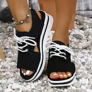 Detailed view of women's black platform sandals featuring white laces and an open-toe design