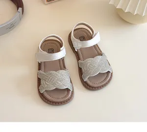 Détail des brides tressées en strass sur sandales blanches pour filles.