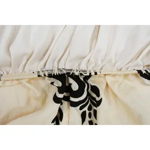 Macro view showing high-quality stitching and black floral print on a cream jumpsuit