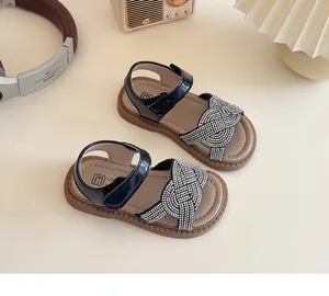 Détail de sandales pour filles en cuir verni noir avec brides tressées en strass
