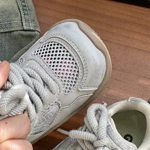 Primer plano de la malla transpirable y los cordones gruesos en zapatillas grises infantiles.