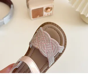 Détail du bracelet tissé en strass étincelant sur des sandales roses élégantes pour filles