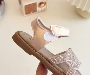 Détail des strass brillants et de la bride velcro sur les sandales roses pour filles